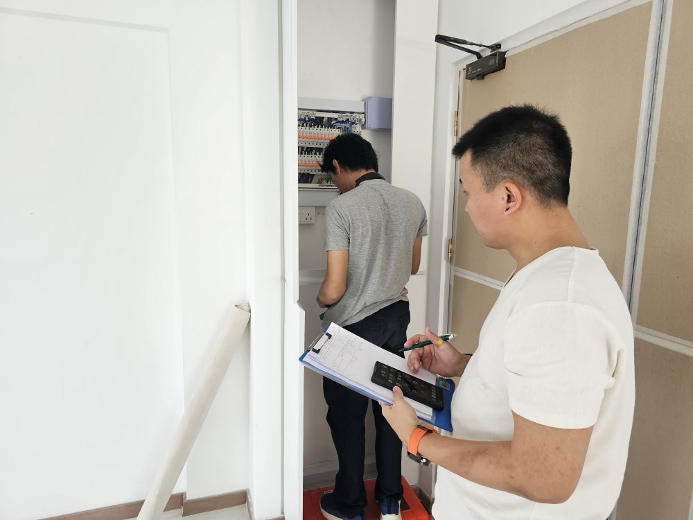Competent Electrician inspecting a distribution board with a clipboard before quoting