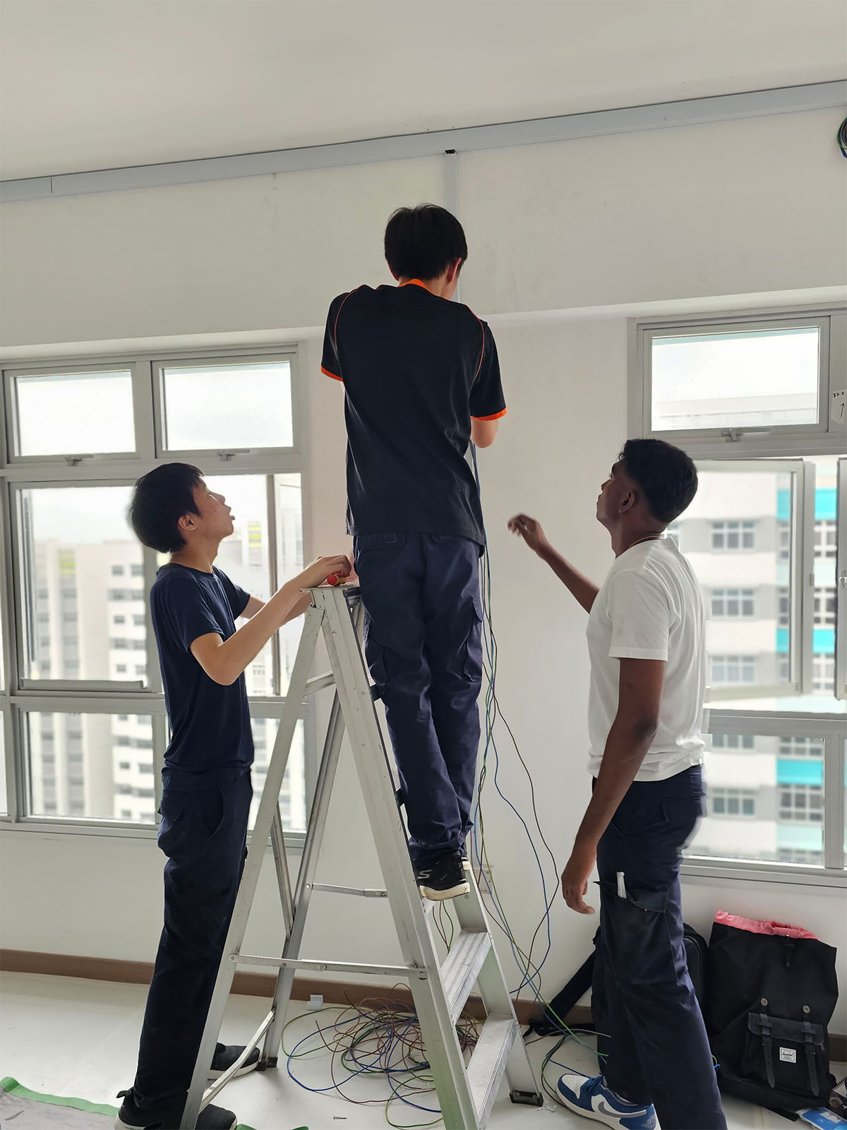 Competent Electrician team running new wiring in the ceiling of an HDB flat